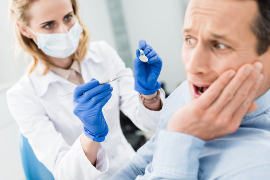 Male patient is afraid of dentist in modern dental clinic