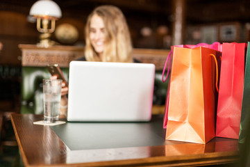 Shopping bags in front of a smiling blond girl with computer on background