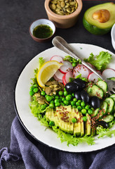 Vegan vegetable salad with flax seeds and olives on a black background