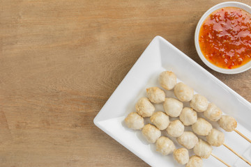 asian style grilled pork balls in a ceramic plate served with sweet  chili sauce on wooden table, top view.