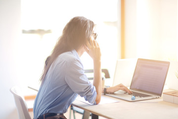 Beautiful young business woman sitting at office desk and talking on cell phone. Business woman