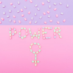 the inscription of  Power and female gender sign laid out with colorful marshmallows on a blue and pink background