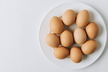 brown eggs laying on white plate on white background