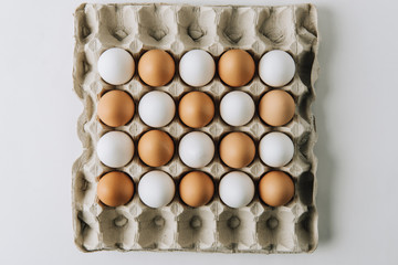 white and brown eggs laying in egg carton on white background