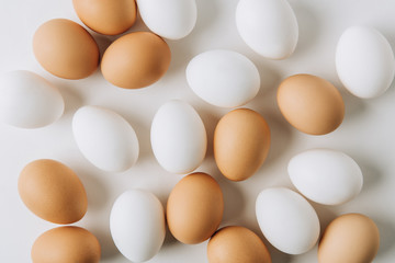 white and brown eggs laying on white background