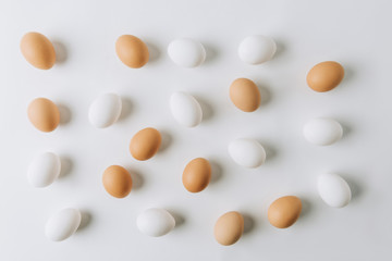 white and brown eggs scattered on white background