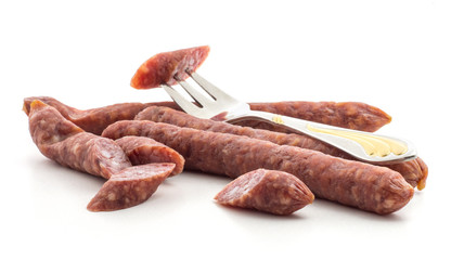 Hungarian dry sausages pepperoni one cut piece impaled on a fork isolated on white background...