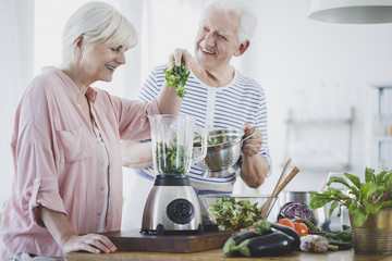 Happy elderly woman preparing smoothie