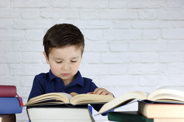 niño pequeño leyendo un libro y rodeado de muchos libros