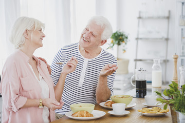 Smiling senior couple eating croissants