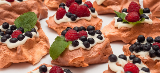 Mini Pavlova meringue nests with berries and mint on isolated on white background