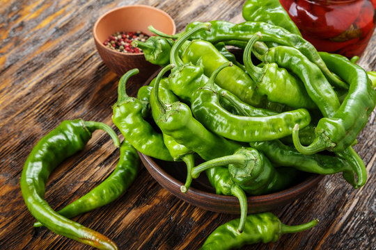 green chili peppers placed in a clay plate on a brown wooden table. with space for text