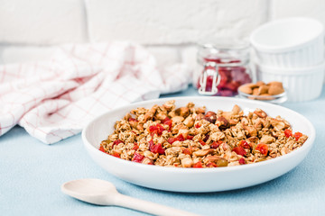 Healthy homemade cranberry granola on light blue background. Selective focus, copy space.