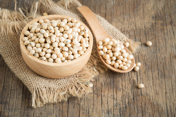 Soybeans in wooden cup and wooden spoon on wood table