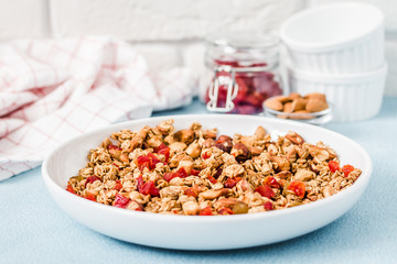 Homemade winter berry granola on light blue background. Selective focus, copy space.
