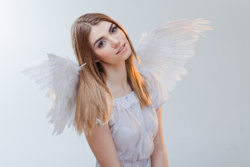 An angel from heaven. Young, wonderful blonde girl in the image of an angel with white wings. Portrait close-up