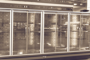 Empty commercial fridges at grocery store in America. Sold out frozen food section. Vintage tone