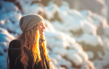 Smiling young woman during walk in the winter park at sunny day