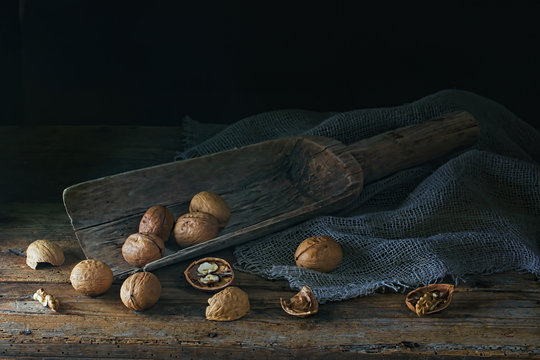.Walnuts in a wooden scoop on an old village table. Low key. Focus concept.