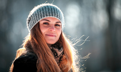 Young woman walking in winter park at sunny day