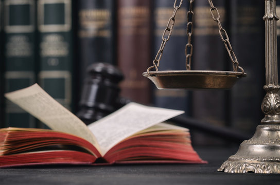 Scales of Justice, Law book and Judge Gavel on a black wooden background.