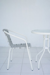 Transparent white table in the cafe. Rattan chair in the background. The whole room is white. Side view with copy space