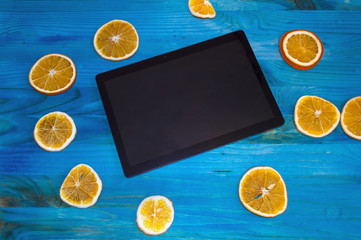 tablet with citrus slices on wooden background
