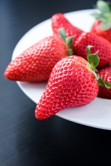 Fresh strawberries on plate on black background