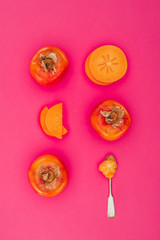 top view of persimmons pieces and spoon isolated on pink