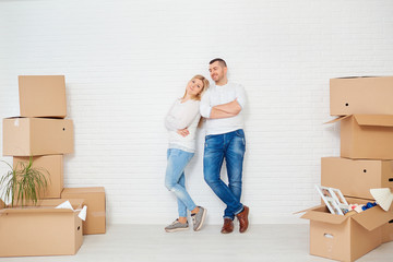 Fototapeta na wymiar A couple with boxes moves to a new house against a white wall. Property For Sale.