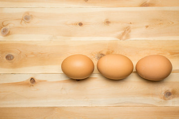 Three chicken eggs lie on a wooden board