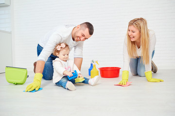 A happy family is washing the floor against a white wall.