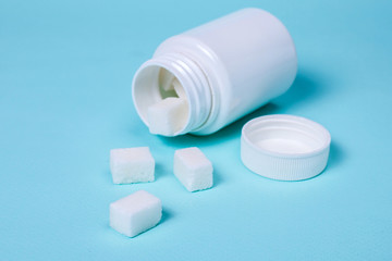 Bottle with tablets in the form of cubes of sugar on a green background