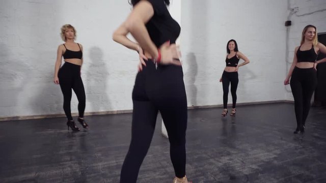 Upward slow-motion footage of a group of attractive sexy women dancing bachata, learning groovy moves.