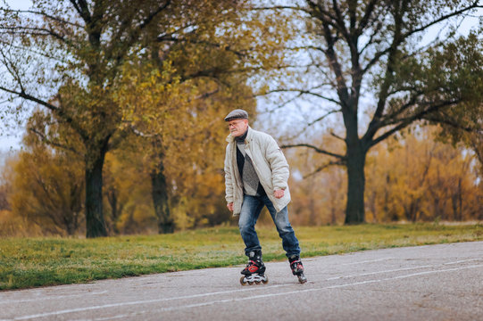 The old man goes on rollers in the autumn park. Happy pension. Active old people.