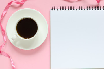 Cup for coffee and notebook on pink background