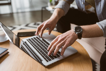 cropped shot of man working with laptop on coffee table
