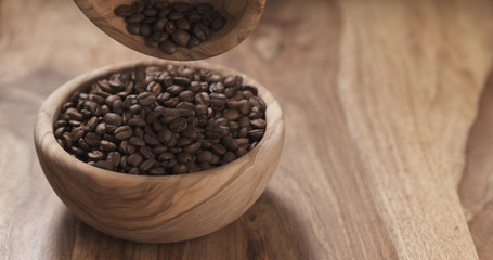 coffee beans falling into wood bowl on table