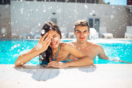 Screaming young teenage girl at the pool annoyed with pool splashing.Splashing water and playing games at the pool,having fun at summer vacation.Getting hair wet in a pool.Hotel pool cold water