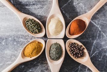 Six light wooden spoons with colorful spices