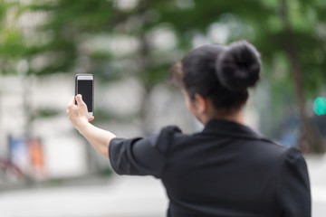 Woman in downtown using smartphone finding location from map application searching.