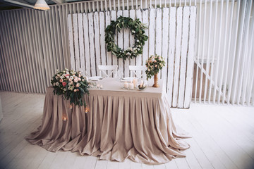 A table for a couple in love, decorated with floral arrangements, against a wooden wall