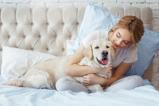 Beautiful teen girl with golden retriever dog in a bed