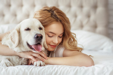 Beautiful teen girl with golden retriever dog in a bed