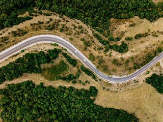 Aerial above view of a rural landscape with a curvy road running through it in Greece. © NBLX