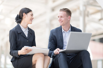 Handsome and Confident Businessman Using Laptop Computer outdoor Discussing With Beautiful Business Partner While sitting on Stairs Way.