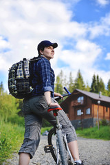 Young woman is traveling with a bicycle in the summer mountains