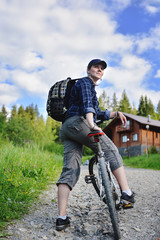 Young woman is traveling with a bicycle in the summer mountains