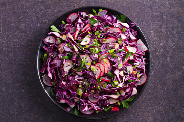 Obraz na płótnie Canvas Red cabbage, radish, spring onion, parsley and sesame seeds salad. Vegetarian salad, healthy food concept. View from above, top, horizontal