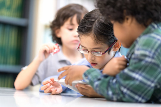 In selective focus of little boys watching Phone. Happy Children Learning Class in Library. Development of Human Resources in Education Concept. Setup studio shooting. - Powered by Adobe